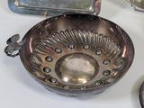 a silver bowl sitting on top of a table next to other silver dishes