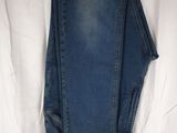 un pantalon en jean suspendu à un portant posé sur un drap blanc
