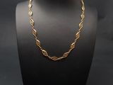 a gold chain necklace on a mannequin with a black background