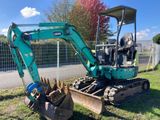 une pelleteuse garée dans l'herbe, près d'une clôture