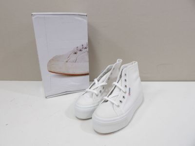 white sneakers with white laces are sitting on a table next to a book