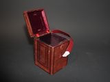 une petite boîte en bois avec une poignée rouge sur un fond noir