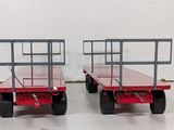 two red trailer trailers sitting side by side on a white floor