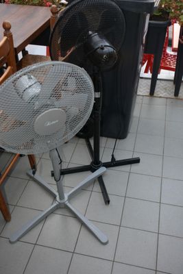 a table with a fan on it and a trash can in the background