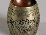 a small gold vase with a floral design on it