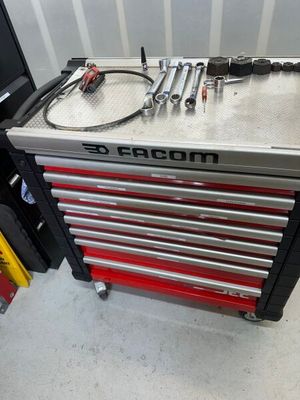 une boîte à outils posée dans un garage, avec des outils dessus