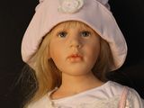 blond haired doll wearing a pink hat and pink dress with white lace