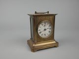 une petite horloge en laiton avec des chiffres romains sur le cadran