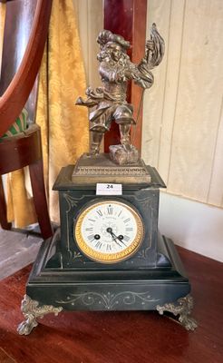 a clock sitting on a table with a statue on top of it