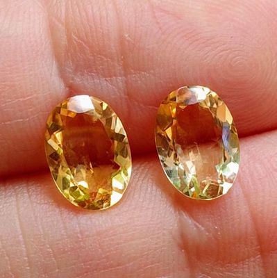 pair of yellow sapphires on a person ' s finger