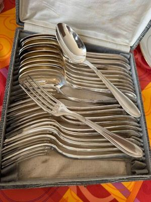 des couverts rangés dans un coffret posé sur une table recouverte d'une nappe colorée
