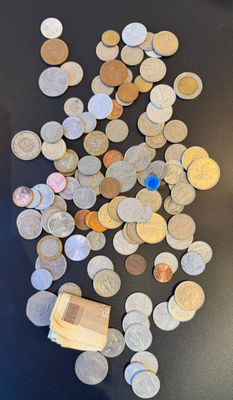 a pile of coins on a table next to a cell phone