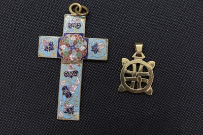 a cross and a small pendant are sitting next to each other