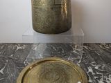a gold plate sitting on a marble table next to a silver vase