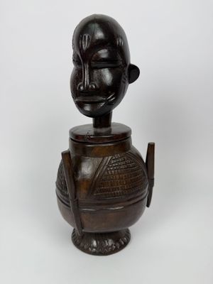un gros plan sur une statue en bois représentant une personne, avec une tête au sommet