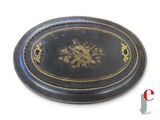 a black oval box with a gold design on it