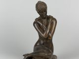 une statue en bronze d'une femme assise sur un rocher