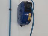 un tuyau bleu fixé au mur à côté des toilettes