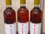 three bottles of wine sitting on top of a wooden barrel