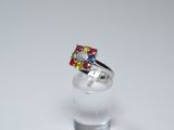 silver ring with multi colored stones on top of a clear glass