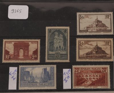 Plusieurs timbres différents sont exposés dans une vitrine posée sur une table.