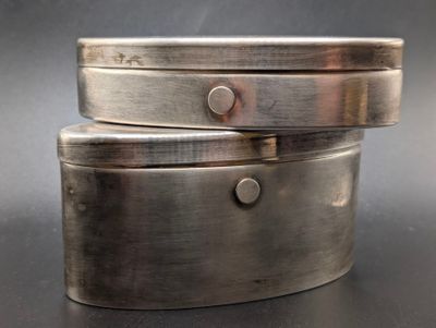 two silver boxes stacked on top of each other on a table