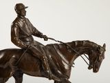 bronze statue of a man riding a horse with a hat on