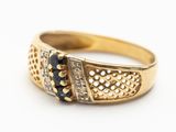 gros plan d'une bague en or avec des diamants noirs et blancs