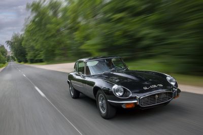 a black car driving down the road with trees in the background
