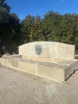 a stone bench sitting in the middle of a dirt field