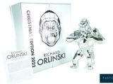 a silver figurine of a man holding a knife in front of a box