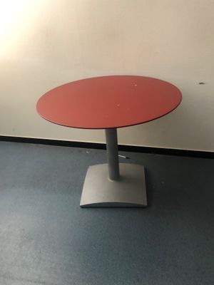 une table rouge avec un piètement en métal dans une pièce