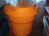 an orange plastic bucket with a lid on a wooden floor