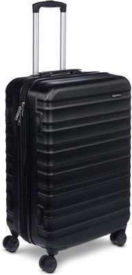 La valise noire repose sur ses roulettes, posée sur une surface blanche.