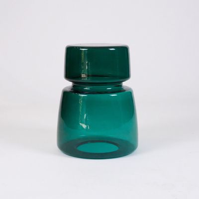 a green glass jar with a green lid on a white surface