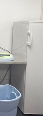 a blue bucket sitting next to a white refrigerator in a room