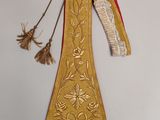 un ancien collier brodé de doré et de rouge, orné de pompons suspendus sur le côté
