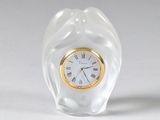 une petite horloge en verre posée sur une table blanche