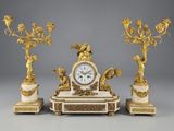 une image représentant une horloge posée sur une table, à côté de trois bougies