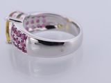 a close up of a white gold ring with pink and yellow sapphires