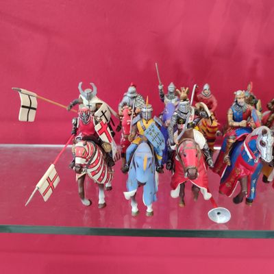 de nombreuses figurines de chevaliers exposées sur une étagère en verre