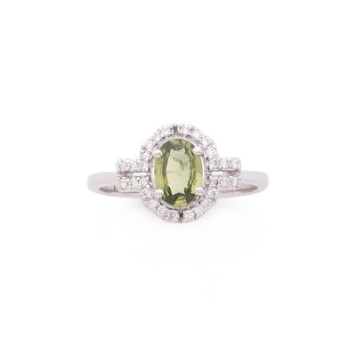 gros plan d'une bague avec une pierre verte entourée de diamants blancs