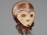 a close up of a wooden mask on a metal stand