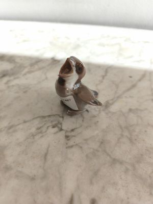 une petite figurine représentant un oiseau perché sur une table en marbre