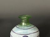 a green vase sitting on a table with a black background