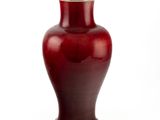 un vase rouge posé sur une surface blanche