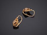 a pair of gold earrings on a black surface