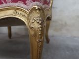 a gold chair with a red upholstered cushion on it