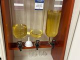 trois verres remplis d'un liquide jaune posés sur une étagère dans une pièce