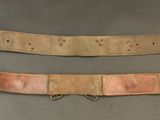 two pieces of leather with metal clasps on a gray surface